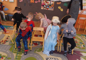 Dzieci z grupy żółtej i pomarańczowej w przebraniach karnawałowych biorą udział w konkursie "wolne krzesełko"