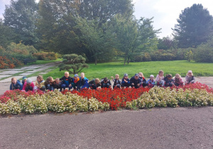 Na zdjęciu dzieci z grupy czerwonej pozują nad kwiatami w Ogrodzie Botanicznym