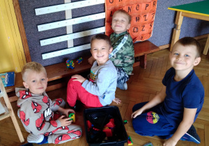 Na zdjęciu 4 chłopców z grupy zielonej dzieci bawią się lego siedząc obok ławki