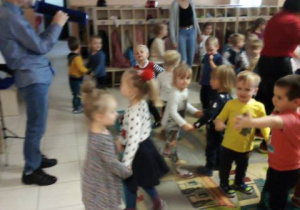 Dzieci tańczą w parach podczas grania przez artystę na melodyce.