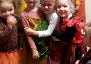 Na zdjęciu dzieci z grupy fioletowej podczas balu jesieni, cztery dziewczynki przebrane w stroje jesienne uśmiechają się do siebie
