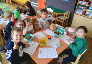 Na zdjęciu dzieci siedzące przy stołach i malujące kolorowanki Misia dzieci sa uśmiechnięte