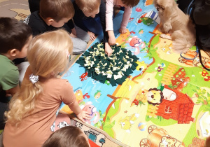 Dzieci ukrywają w zielono-kremowym dywaniku węchowym przysmaki dla piesków.
