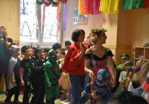Na zdjęciu dzieci z grupy czerwonej tańczą ustawione jedno z drugim wraz z pracownikami przedszkola
