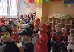 Na zdjęciu dzieci przebrane w stroje karnawałowe tańczą i klaszczą podczas tańca