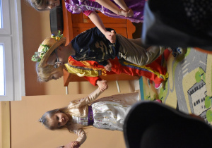 Na zdjęciu czwórka dzieci z grupy fioletowej tańczą w kółeczku dzieci są przebrane w stroje karawałowe