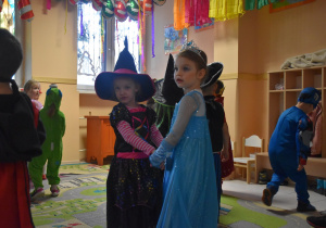 Na zdjęciu dwie dziewczynki z grupy fioletowej przebrane za księżniczkę i czarodziejkę tańczą ze sobią