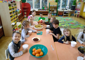 Na zdjęciu dzieci z grupy zielonej siedzą przy połączonych stołach dzieci przygotowują się do wykonywania sałatek owocowych