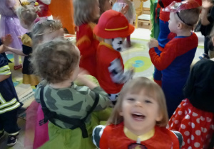 Dzieci w strojach karnawałowych tańczą w rytm muzyki.