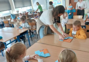 Na zdjęciu dzieci z grupy czerwonej siedzą w szkolnych ławkach w SP nr 182 w Łodzi i wykonują kapelusze z papieru