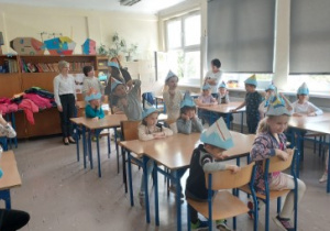 Na zdjęciu dzieci z grupy czerwonej siedzą w szkolnych ławkach w SP nr 182 w Łodzi dzieci mają na głowie wykonane podczas zajęć czapki z papieru