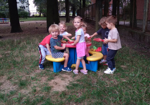 Na zdjęciu dzieci z grupy żółtej podczas pobytu w ogrodzie dzieci bawią się przy plastikowym kolorowym stoliku