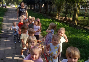 Na zdjęciu dzieci z grupy żółtej podczas spaceru wokół przedszkola dzieci idą w parach trzymając gąsienice ze sznurka, dzieci są uśmiechnięte