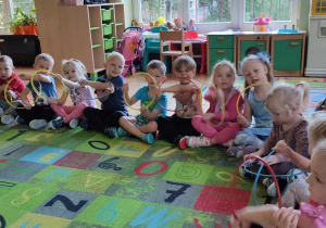 Na zdjęciu dzieci z grupy zielonej podczas obchodów Dnia przedszkolaka dzieci bawią się na dywanie trzymają w ręku obręcze, którymi obracają