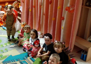 Na zdjęciu dzieci podczas balu jesieni siedzą w kole na tel dekoracji jesiennej, na środku koła stoi chłopczyk