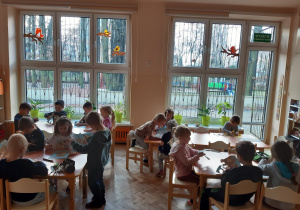Dzieci siedzą przy stolikach. Wycinają z papieru sylwetkę misia.