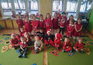 Na zdjęciu dzieci ubrane na czerwono w strojach świątecznych, dzieci są uśmiechnięte