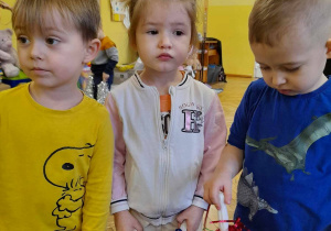 N zdjęciu trójka dzieci z grupy żółtej dzieci mają w rękach kolorowe pompony