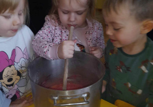 Na zdjęciu troje dzieci podczas wykonywania ciasta na babeczki, dzieci mieszają masę w garku