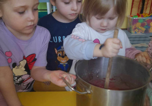 dczas wykonywania ciasta na babeczki, dzieci mieszają masę w garku