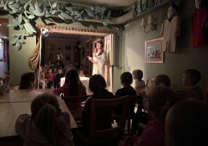 Na zdjęciu chłopcy i dziewczynki z grupy fioletowej siedzący przy stoliku w teatrze Baśniowa Kawiarenka