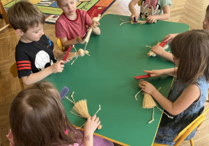 Na zdjęciu dzieci z grupy fioletowej podczas wykonywania laleczki ze sznurka, dzieci wyczesują kolorowy sznurek grzebieniem