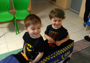 Na zdjęciu dwóch chłopców z grupy żółtej przebrani w samochód Straży Miejskiej