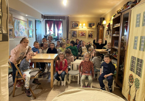 Na zdjęciu dzieci z grupy czerwonej podczas wycieczki do Baśniowej Kawiarenki, dzieci siedzą przy stole i czekają na spektakl
