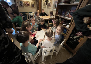 Na zdjęciu dzieci z grupy czerwonej podczas wycieczki do Baśniowej Kawiarenki, dzieci siedzą przy stole i częstują się poczęstunkiem