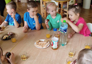 Na zdjęciu dzieci podczas jedzenie przysmaków z pikniku, dzieci siedzą przy stole i wspólnie spędzają czas