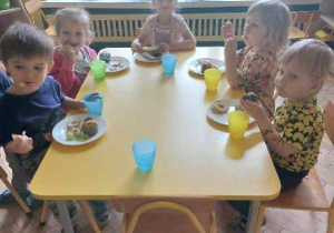 Na zdjęciu dzieci z grupy żółtej podczas jedzenia przysmaków z pikniku, dzieci siedzą przy stole