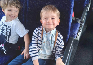 Na zdjęciu dwóch chłopców podczas podróży autokarem chłopcy się uśmiechają