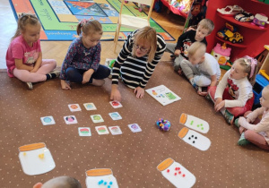 Na zdjęciach dzieci z grupy zielonej dzieci siedzą na dywanie i oglądają prezentowane przez pedagoga emocję