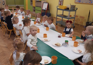 Dzieci siedzą przy wspólnym stole, jedząc zdrowe śniadanie.