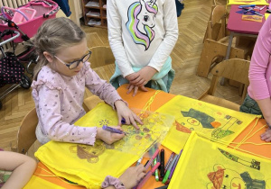 Na zdjęciu dziewczynki kolorujące żółte worki