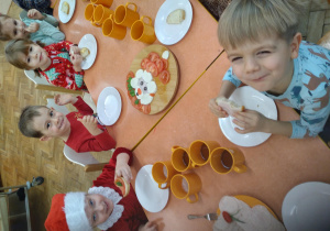 Na zdjęciu dzieci z grupy pomarańczowej dzieci siedzą przy stole podczas śniadania