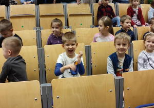 Na zdjęciu dzieci z grupy zielonej siedzą w sali i czekają na spektakl