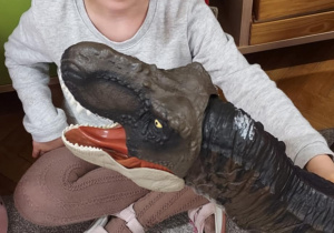 Na zdjęciu dziewczynka oglądająca dinozaura