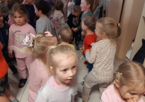 Dzieci ubrane w pidżamy tańczą w rytm muzyki na beżowej podłodze.