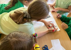 Na zdjęciu dzieci z grupy czerwonej podczas wykonywania gry planszowej