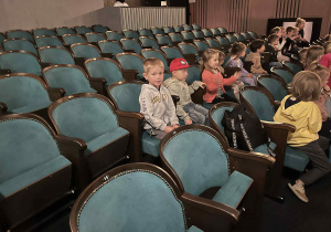 Na zdjęciu dzieci z grupy pomarańczowej podczas pobytu w teatrze dzieci siedzą na widowni i czekają na spektakl