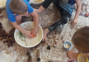 Na zdjęciu kilkoro dzieci podczas zajęć sensoplastycznych dzieci bawią się materiałami spożywczymi