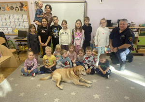 Na zdjęciu dzieci pozują z psem oraz funkcjonariuszem Straży Miejskiej