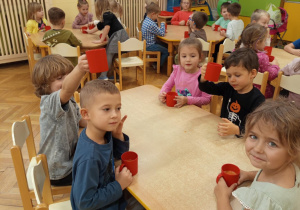 Na zdjęciu dzieci siedzące przy stole dzieci piją wykonany samodzielnie soczek