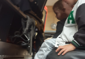 Chłopiec i dwie dziewczynki siedzą we wnętrzu strażackiego wozu.