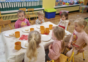 Na zdjęciu dzieci siedzące przy przystrojonym stole dzieci spożywają wspólnie śniadanie mikołajkowe