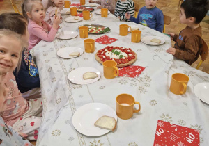 Na zdjęciu dzieci siedzące przy przystrojonym stole dzieci spożywają wspólnie śniadanie mikołajkowe