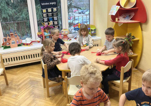 Na zdjęciu dzieci siedzą przy stołach i wykonują mikołaja ze sznurka, dzieci szczotkują sznurek