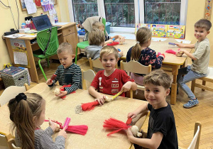 Na zdjęciu dzieci siedzą przy stołach i wykonują Mikołaja ze sznurka, dzieci szczotkują sznurek