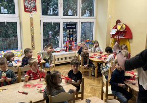 Na zdjęciu dzieci siedzą przy stołach i wykonują Mikołaja ze sznurka